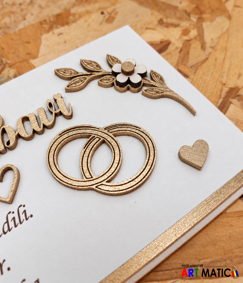 Pola stoljeća ljubavi – detalj vjenčanih prstenova Detalj zlatnih drvenih vjenčanih prstenova, srca i cvjetnog ukrasa na okviru za 50. godišnjicu braka.